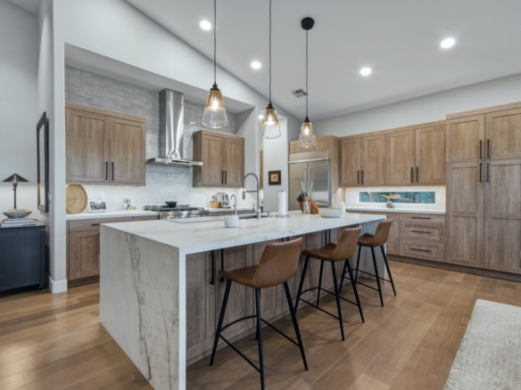 Image of a luxury home kitchen with waterfall edge island and warm colored cabinets.