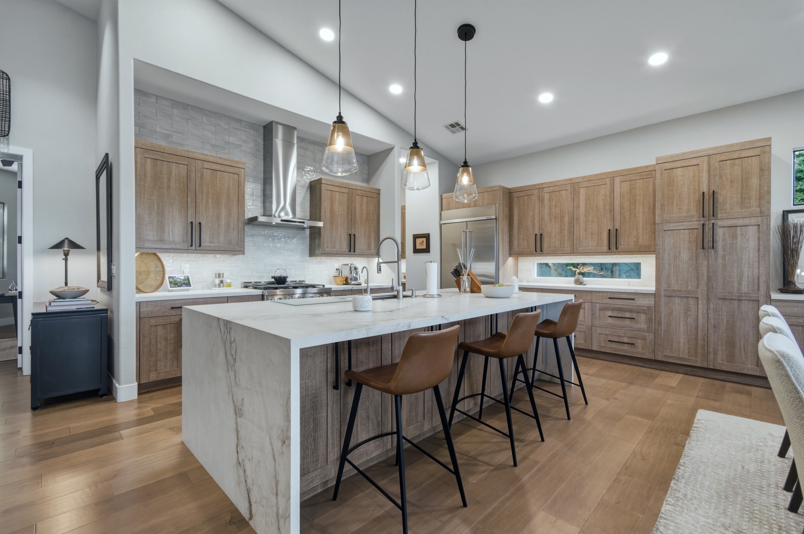 Image of a luxury home kitchen with waterfall edge island and warm colored cabinets.