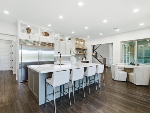 Modern open-concept kitchen in a Las Vegas home featuring a large island with seating, stainless steel appliances, white cabinetry, and wood-look flooring