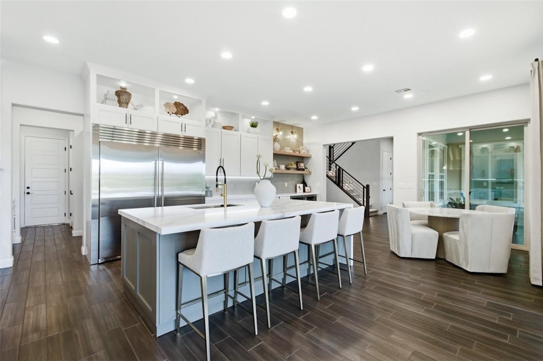 Modern open-concept kitchen in a Las Vegas home featuring a large island with seating, stainless steel appliances, white cabinetry, and wood-look flooring