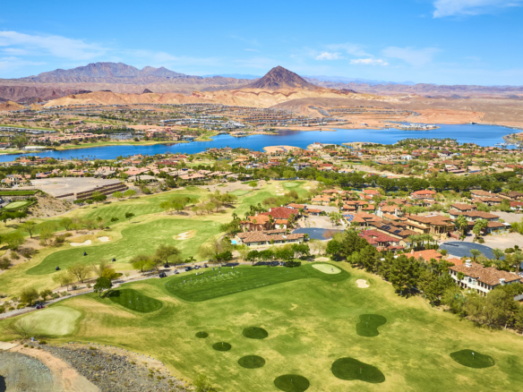 Aerial view of Lake Las Vegas featuring waterfront homes, a championship golf course, desert mountains, and the lake surrounded by luxury communities in Henderson, Nevada.