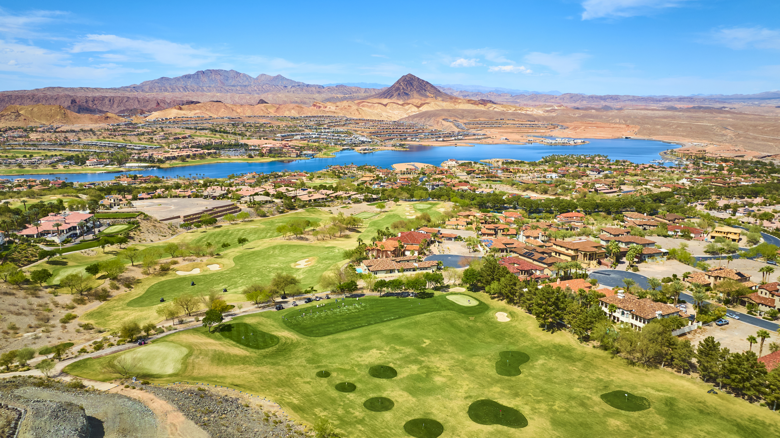 Aerial view of Lake Las Vegas featuring waterfront homes, a championship golf course, desert mountains, and the lake surrounded by luxury communities in Henderson, Nevada.